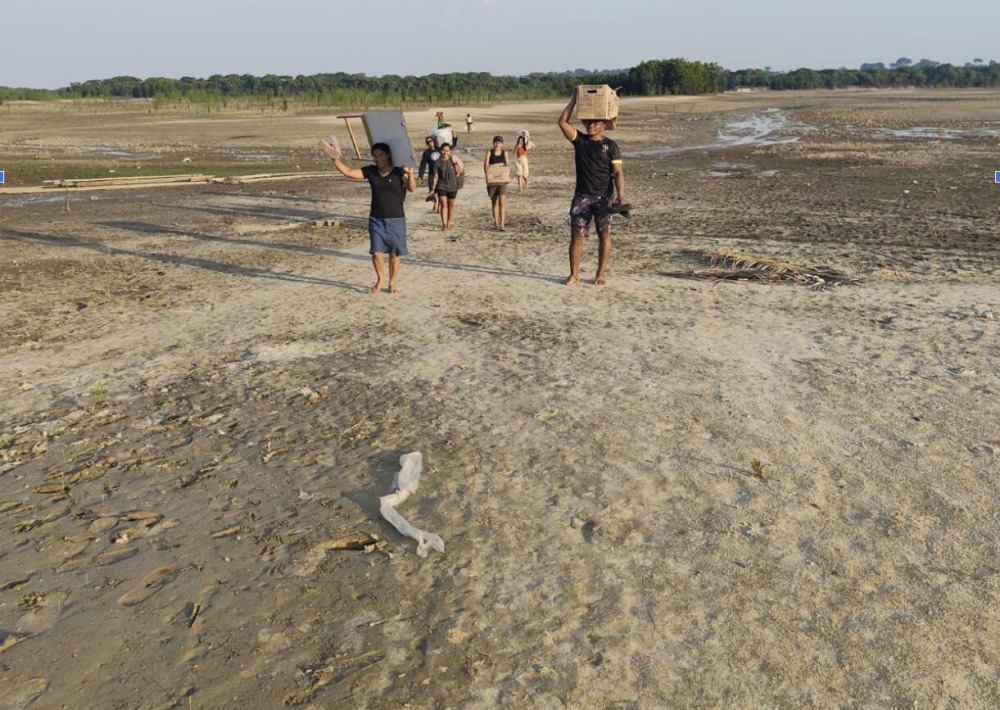 Quilombola community members carrying water, walking through what usually is the bottom of Lake Tefé. Photo taken on Sept 07 2024. Photo courtesy of IIEB